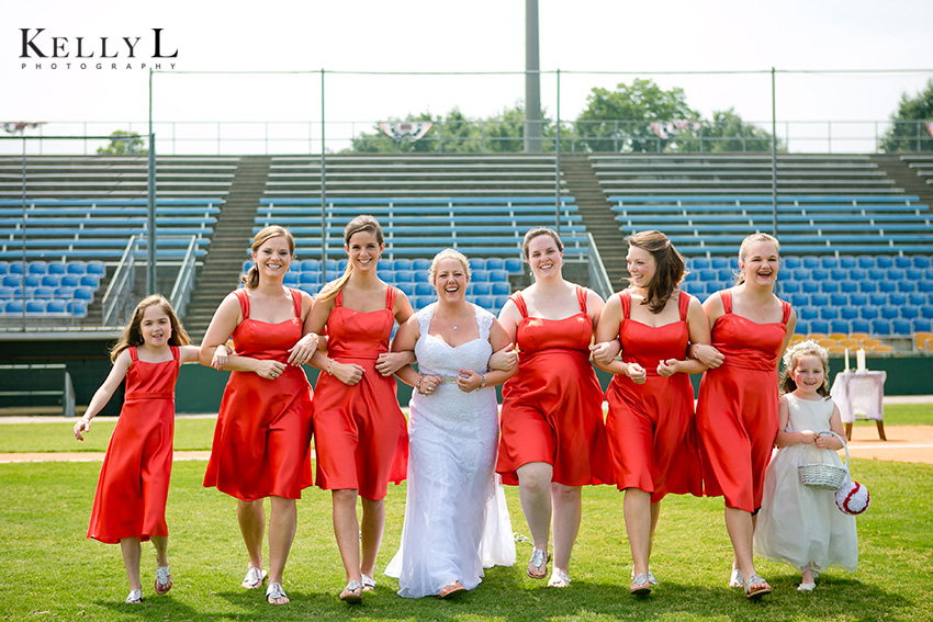 bridesmaids laughing together on baseball field