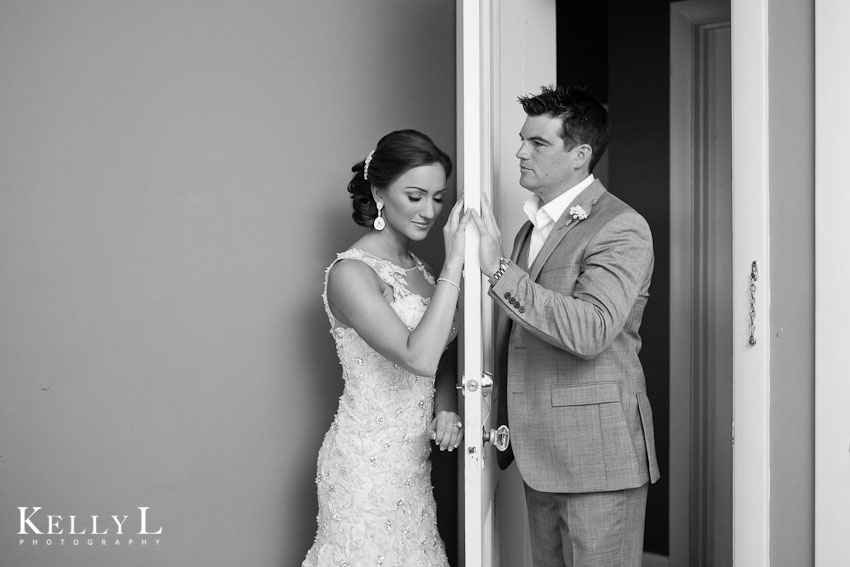 bride and groom hold hand behind door before wedding